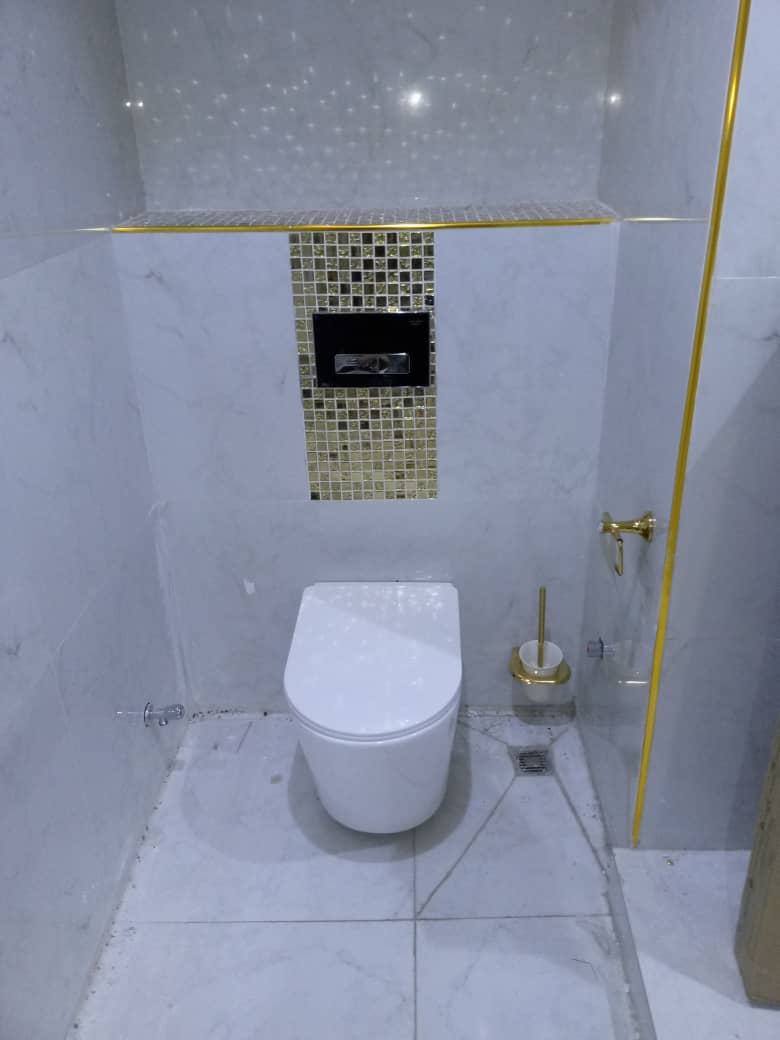 Wall-hung toilet with gold mosaic concealed cistern panel